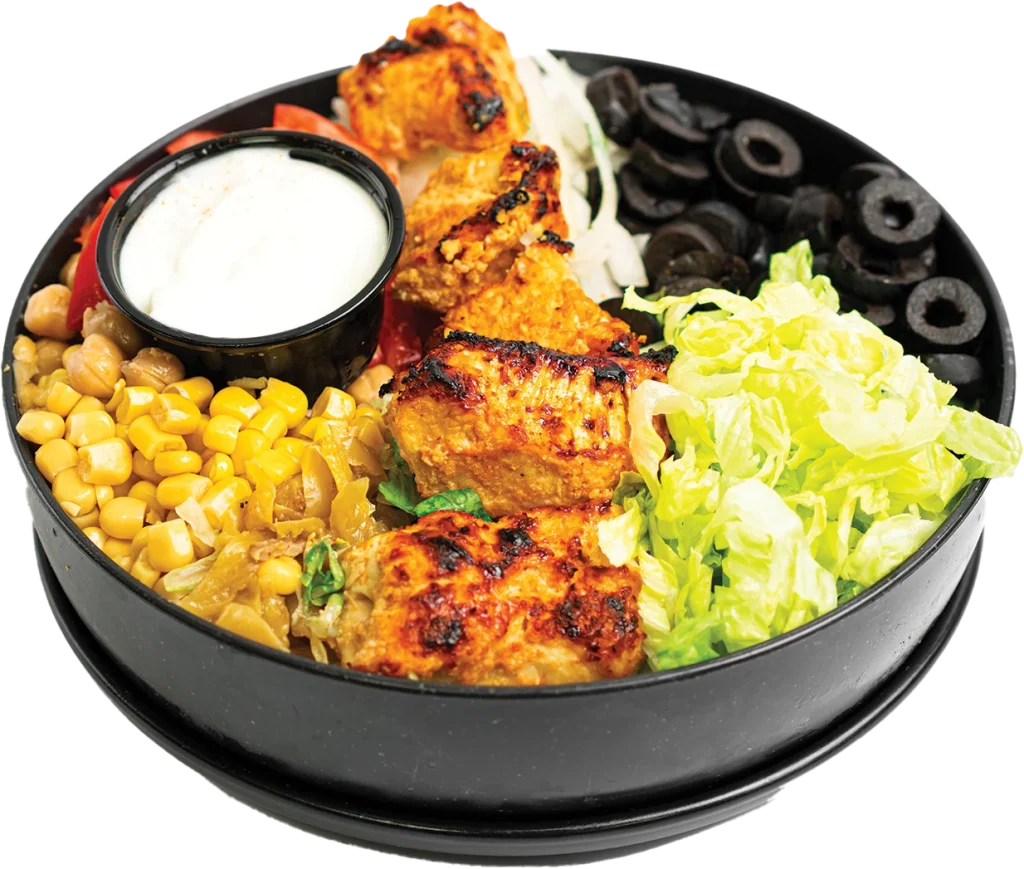 Grilled chicken kabob cubes over a salad of lettuce, tomatoes, corn, chickpeas and olives